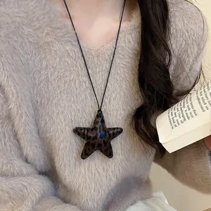 Leopard print star pendant necklace with leather texture on grey sweater