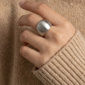 Close-up of a wide silver matte stainless steel ring on a model wearing a beige sweater