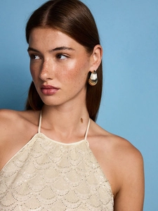 Golden shell texture earrings worn by a model in a stylish sequined halter top dress