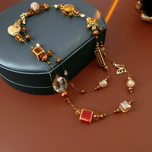 Détail d'un collier bohème avec perles en céramique marron et breloques dorées
