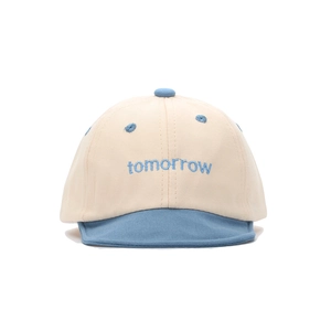 Détail de la broderie 'tomorrow' sur casquette bébé en coton avec texture douce et fine