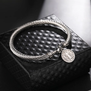 Macro detail of silver stainless steel twisted cable bracelet with religious medal charm
