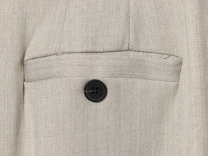 Detailed macro view of light khaki twill fabric featuring a pocket and black button