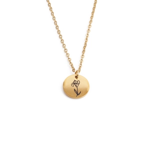 Close-up of golden stainless steel round pendant with minimalist black flower engraving