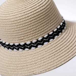 Detailed view of the woven straw sun hat with black and white wavy ribbon texture