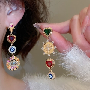 Detail of asymmetrical heart earrings with Evil Eye and Hamsa Hand in bohemian style
