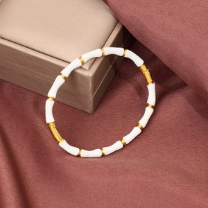 Detail view of gold-plated bamboo joint bracelet with white enamel inserts and buckle closure