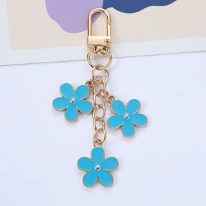 Detail of three blue enamel flower charms on a golden metal keychain with spring clasp
