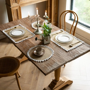 Detail of woven jute table runner with fringe on a rustic wooden dining table