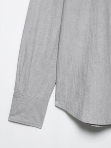 Close-up of grey loose shirt fabric showing natural linen texture and fine stitching detail