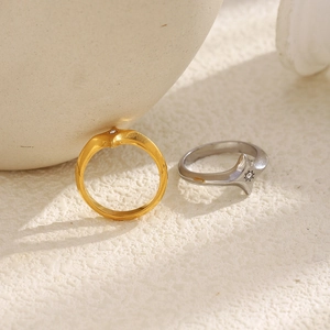 Detailed close-up of 18K gold and silver star rings with zircon inlay on a stone base