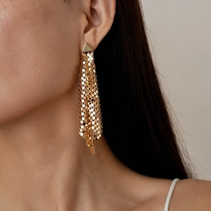 Close-up of golden fringe mesh earrings featuring a long geometric tassel design