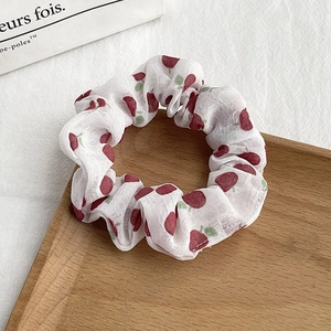 Detailed view of floral scrunchie with red cherry pattern on soft white chiffon fabric