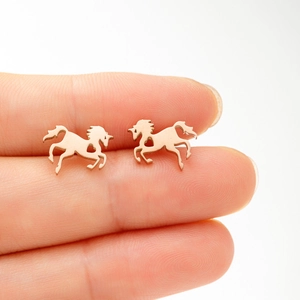 Chic rose gold unicorn stud earrings with heart cutouts shown on a finger for scale