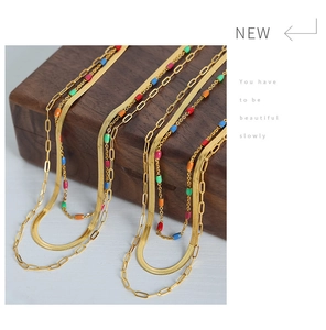 Détail d'un collier doré multi-rangs avec perles en émail coloré sur boîte de présentation