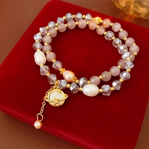 Détail d'un bracelet double couche en perles avec pendentif Saturne sur velours rouge