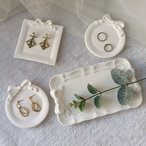 White ceramic jewelry tray set with embossed bows, includes rectangular and round shapes