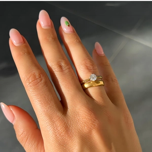 Détail de bagues dorées superposées avec zircon solitaire et anneau large poli
