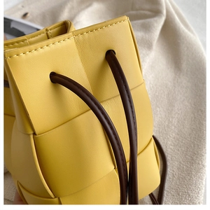 Close-up of yellow woven PU leather bucket bag detailing and contrast drawstring