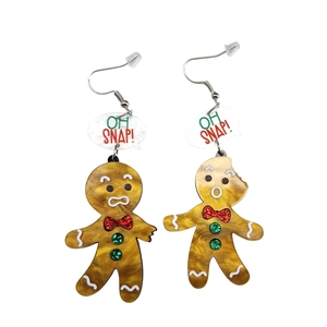 Detailed view of bitten gingerbread man acrylic earrings with glitter and Oh Snap text