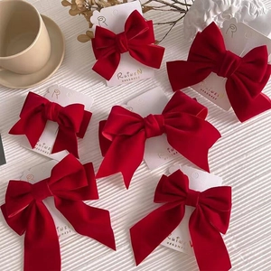 Elegant red velvet bow hair clips and spring clips displayed on a white textured background
