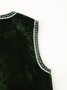 Detail of dark green velvet vest featuring silver sequins and white geometric embroidery