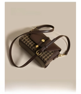 Macro view of adjustable leather strap and golden metal buckle on houndstooth bag
