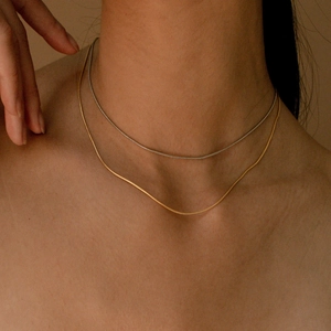Detail of minimalist 18K gold and silver plated stainless steel snake chains worn on neck