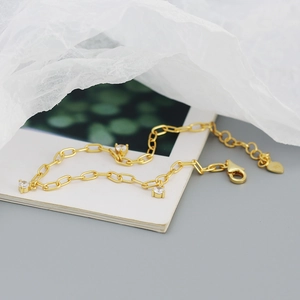 Detail of s925 silver gold bracelet with heart charms and white zircon on white card