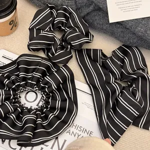 Classic black and white striped silk scrunchie set on a minimalist cozy knit background