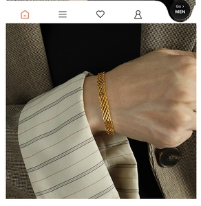 Detailed close-up of a golden mesh woven bracelet worn with a professional plaid suit