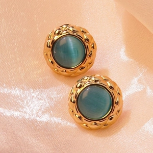Macro shot of vintage gold button earrings with quilted texture and blue gemstones
