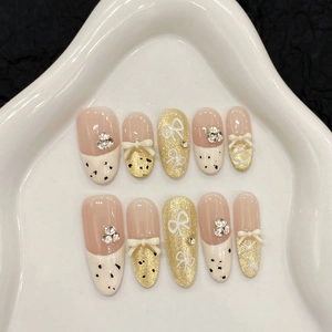 French bow press-on nails set with creamy white cat-eye effects and golden rhinestones