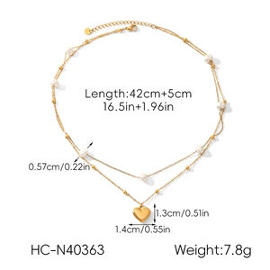 Detailed view of double-layer gold necklace with heart pendant and small white pearls