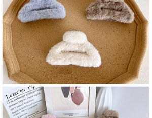 Trois grandes pinces à cheveux en peluche bleu clair, marron et beige sur un plateau