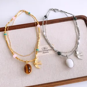 Détail d'un collier vintage bohème double épaisseur avec pendentif hirondelle et perles