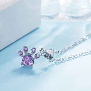 Close-up of heart-shaped purple gemstone cat paw pendant on a silver metal chain