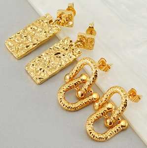 Detailed close-up of gold horseshoe buckle earrings with textured hammered finish