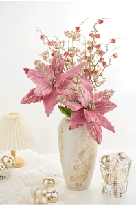 Gros plan sur un poinsettia rose en velours avec paillettes dorées pour Noël