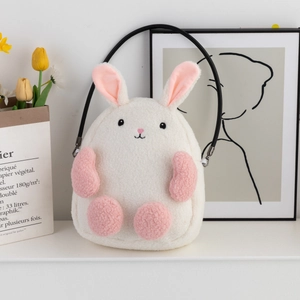 Detail view of a white plush bunny shoulder bag with pink accents and black strap
