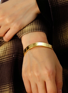 Close-up of a minimalist gold-plated irregular C-shape bangle worn on the wrist