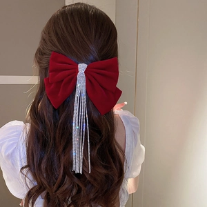 Macro view of burgundy velvet bow hair clip with crystal tassels and sparkling rhinestones