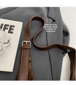Detail of adjustable brown leather shoulder strap with polished silver metal buckle