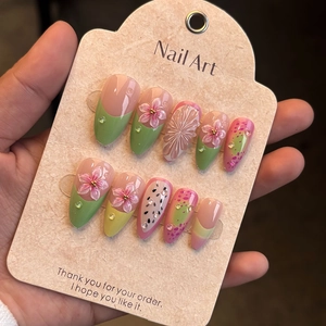 Detailed macro shot of 3D pink floral nail art with green french tips and crystal accents