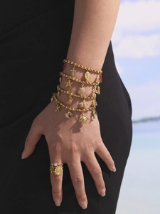 Detail von goldenen Edelstahl-Armbändern und Ringen am Modell in Strandumgebung