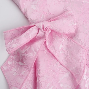 Close-up of pink jacquard fabric detail featuring a large elegant bow and floral patterns