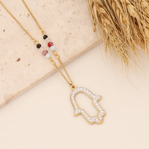 Detail of gold Hamsa pendant with hollow outline and colorful beads on a gold chain