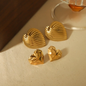 Detailed view of gold stainless steel heart earrings with textured and geometric designs