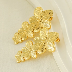 Detailed macro view of triple golden flower earrings with delicate brushed metal texture