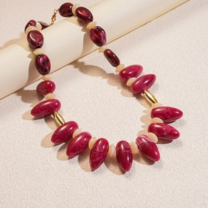 Close-up of burgundy resin beads with marble texture and gold metal accents on necklace